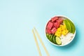 Tuna poke bowl with rice, avocado, mango and cucumber on blue. Royalty Free Stock Photo