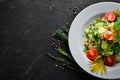 Tuna salad and fresh vegetables on a black background. Free space for your text. Royalty Free Stock Photo