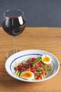 Tuna salad with vegetables, boiled eggs, cherry tomatoes and spices and one glass of red wine over wooden background Royalty Free Stock Photo