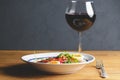 Tuna salad with vegetables, boiled eggs, cherry tomatoes and spices and one glass of red wine over wooden background Royalty Free Stock Photo