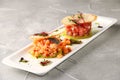 Tuna and salmon tartare with avocado on white plate and concreter background