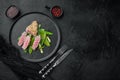 Tuna tataki sesame crust appetizer with spring onions and sugar snap peas , on plate, on black stone background, top view flat lay Royalty Free Stock Photo