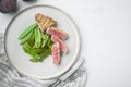 Tuna tataki sesame crust appetizer with spring onions and sugar snap peas, on plate, on white stone  background, top view flat lay Royalty Free Stock Photo