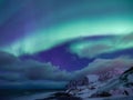 Tungeneset rocks and Aurora Borealis light. Senja islands, Norway. Stars trails and northern light. Reflections on the water surfa