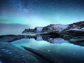 Tungeneset rocks and Aurora Borealis light. Stars trails and northern light. Reflections on the water surface. Senja islands, Norw