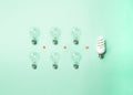 Tungsten light bulbs and energy-saving bulb on green background