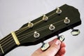 Tuning an acoustic guitar. White background. Close-up.