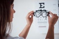 Tuning the device. Photo from behind. Woman looking through the glasses eye chart