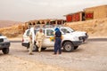 Drivers of tourist jeeps rest near cars, while tourists dine in the cafe and buy souvenirs, Sahara