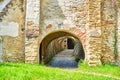 Tunnel with multiple arches and cobblestone going through a brick stone wall, from the green grass outside to the interior. Royalty Free Stock Photo