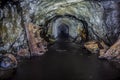The tunnel of an old abandoned mine with rusty remnants of trolleys Royalty Free Stock Photo