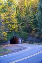 The tunnel through the rock with autumn trees at the top and the turn of the road Royalty Free Stock Photo