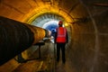 Tunnel worker examines pipeline in underground tunnel