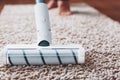 The turbo brush of a cordless vacuum cleaner cleans the carpet in the house in close-up Royalty Free Stock Photo