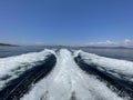 turbulent wake waves caused by a fast moving boat with a bright blue cloudless sky Royalty Free Stock Photo