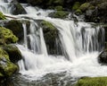 Turbulent waterfall rushing over a steep cliff at a popular toursit destination, with mossy rocks. Royalty Free Stock Photo