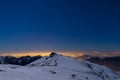 Turin city lights, night view from snow covered Alps by moonlight. Moon and Orion constellation, clear sky. Italy.