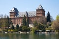 Valentino castle red bricks facade and Po river banks with people in Piedmont, Turin, Italy