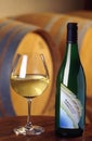 Turin, Piedmont, Italy. -10/26/2009- Fair `Wine show` bottle and glass of white wine Chardonnay with barrels on background. Royalty Free Stock Photo