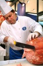 Turin, Piedmont, Italy. -10/22/2010- The food fair `Salone del Gusto`. Grocer slices the traditional italian mortadella di Bologna