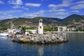 Men fish on rocks near a small lighthouse in the port of Alanya. Cityscape of turkish town with