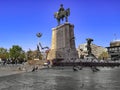 Ulus Square and pigeons flying around the Victory Monument in Ankara. A man sits in the city