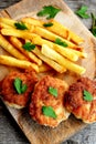 Turkey breast cutlets served with deep fried potatoes on cutting board and on an old wooden background. Closeup. Top view Royalty Free Stock Photo