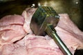 Turkey meat cut into pieces and a hammer for beating the meat. Close-up, surface texture Royalty Free Stock Photo