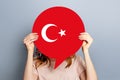 Female hands holding a round information piece of paper dialog with turkish flag emblem isolated over grey studio