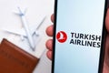 Turkish Airlines app on a smartphone screen with a plane and passport on the background. The concept of travel app