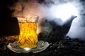 Turkish Azerbaijan tea in traditional glasse and pot on black background with lights and smoke. Armudu traditional cup Royalty Free Stock Photo