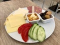 Turkish Breakfast Plate with Honey, Butter Cream Kaymak, Cheese, Cucumber Slices, Olives, Ham and Tomatoes.