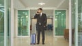 Turkish business man person with suitcase luggage walking to hall corridor and using mobile smartphone in a hotel in business trip Royalty Free Stock Photo