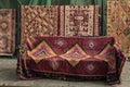 Turkish carpets displayed on the street some hanging and one draped over a seat with flower petals from the trees fallen around Royalty Free Stock Photo