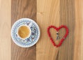 Turkish coffee and heart shaped red rosary on brown table