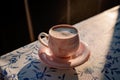 Turkish coffee in a pink cup with a saucer in the sun close-up. Coffee break.
