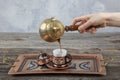 Turkish coffee. Pouring Turkish coffee into vintage cup on wooden background. Pouring Turkish coffee into traditional embossed Royalty Free Stock Photo