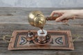 Turkish coffee. Pouring Turkish coffee into vintage cup on wooden background. Pouring Turkish coffee into traditional embossed Royalty Free Stock Photo