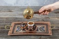 Turkish coffee. Pouring Turkish coffee into vintage cup on wooden background. Pouring Turkish coffee into traditional embossed Royalty Free Stock Photo