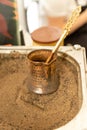 Turkish coffee prepared on hot sand for an unique taste and aroma. Traditional oriental beverage in copper cezve Royalty Free Stock Photo