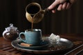 Turkish coffee. Woman pouring brewed beverage from cezve into cup at wooden table, closeup Royalty Free Stock Photo