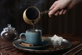 Turkish coffee. Woman pouring brewed beverage from cezve into cup at wooden table, closeup Royalty Free Stock Photo