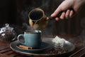 Turkish coffee. Woman pouring brewed beverage from cezve into cup at wooden table, closeup Royalty Free Stock Photo