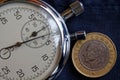 Turkish coin with a denomination of one lira (back side) and stopwatch on dark worn blue jeans backdrop - business background Royalty Free Stock Photo