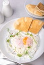 Turkish eggs (chilbir) with yogurt, fragrant butter, pea sprouts, flatbread and tea. Traditional Turkish breakfast.