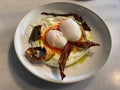 Turkish eggs cilbir in a white bowl. Turkish cuisine concept. Poached eggs with yogurt and spicy butter sauce, close-up