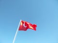 The Turkish flag flies in the wind on a flagpole against the blue sky. The national red and white flag of the country of Turkey is Royalty Free Stock Photo