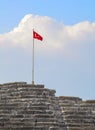 Turkish flag on top of an ancient amphitheater against the backdrop of a large cloud close-up