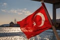 The Turkish flag waving over the Bosphorus. Istanbul Ortakoy Mosque at the background.