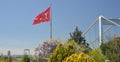 The Turkish flag is waving in the wind in a park overlooking the bridge over the Bosphorus and beautifully blooming Royalty Free Stock Photo